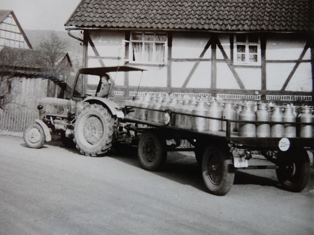 Schwarz-weiß Fotografie eines Traktors mit Dutzenden Milchkannen auf dem Anhänger, ca. 1950er Jahre - Heimat.Museum.Südniedersachsen